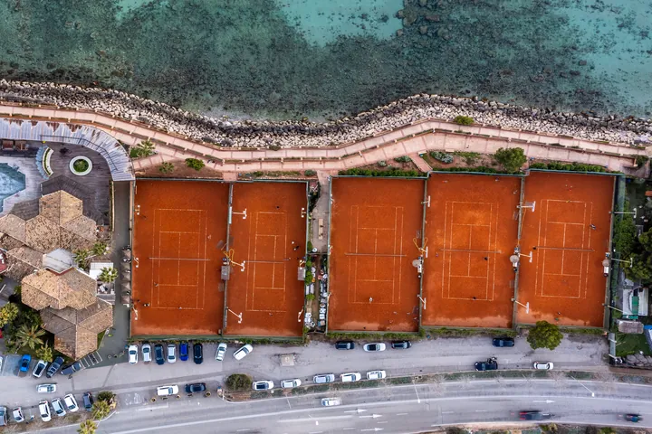 Tennisanlage mit roten Sandplätzen direkt am Meer auf Mallorca, aus der Luft