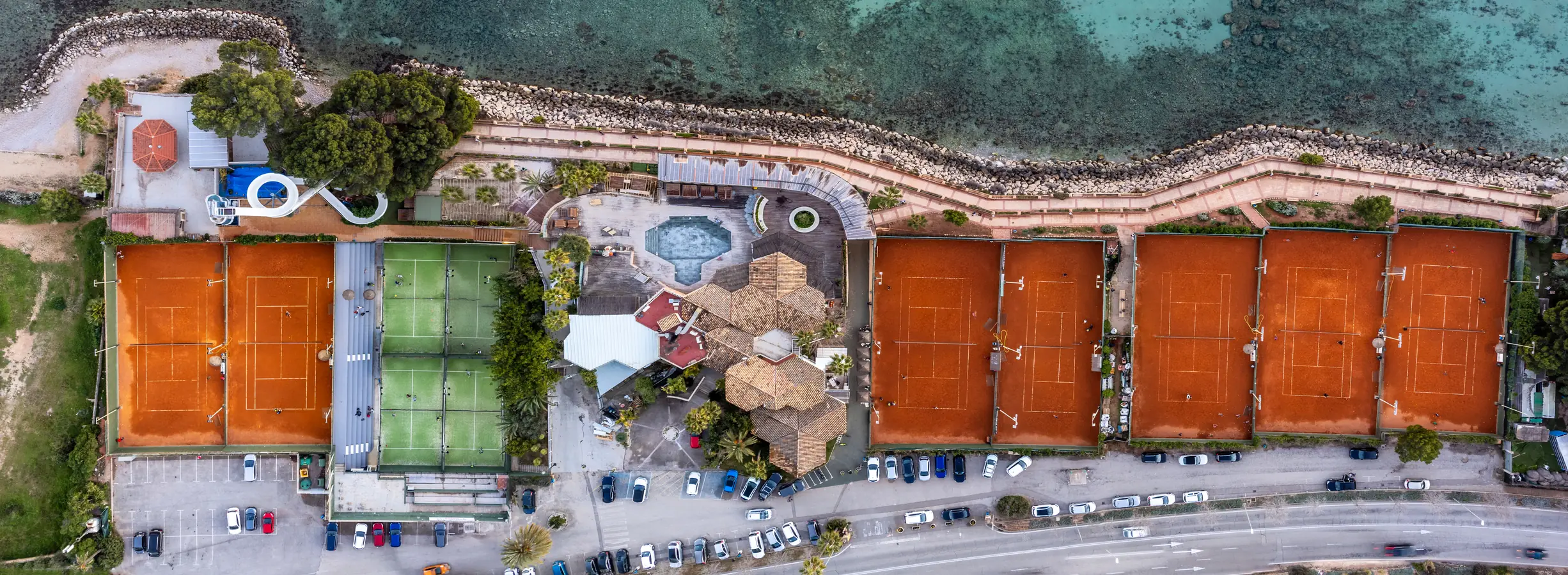 Tennisanlage mit roten Sandplätzen direkt am Meer auf Mallorca, aus der Luft